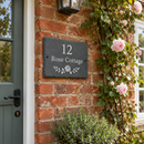 Personalised slate house sign with the name Rose Cottage beside the front door of a cottage