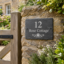 Personalised slate house sign with the name Rose Cottage on a garden wall by a gate