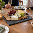 Personalised slate serving and cheese board with the name The Taylors with cheese and grapes at a dinner party