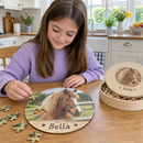 Personalised wooden jigsaw: a young girl sitting at a kitchen table assembling a personalised round wooden photo jigsaw showing her pony and the name 'Bella', the presentation case open beside her