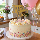 Personalised glitter cake topper on a cake in a kitchen