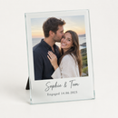 Personalised glass photo frame printed with an engagement photo of a couple and the text Sophie & Tom and Engaged 14.06.2025, on a plain background