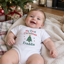 My first Christmas baby grow with the name Freddie worn by a baby under a Christmas tree