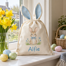 Personalised Easter basket bag with the name Alfie beside daffodils on a windowsill
