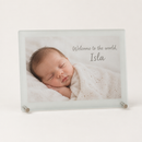 Personalised frosted glass photo frame printed with a soft photo of a newborn baby sleeping and the message Welcome to the world, Isla, on a plain background