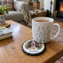 Personalised slate photo coaster, with a mug of tea on it on a wooden coffee table in a cosy UK living room