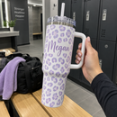 Hand holding a leopard-print name tumbler in a gym
