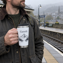 White travel mug with a name held on a station platform