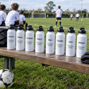 Team water bottles with names lined up beside a football pitch