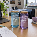 Two name glass cups with bamboo lids on a desk