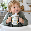 Toddler holding a name sippy cup in a high chair
