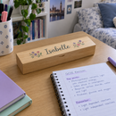 Slim wooden pencil case with a name on a desk