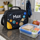 Black lunch bag with planets and a name on a kitchen worktop