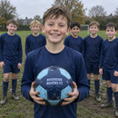 Junior player holding a personalised football printed with his grassroots team name