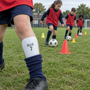 Child at football training wearing white printed shin pads with name and number