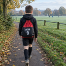 Boy carrying a drawstring boot bag printed with his name and number to football