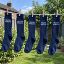 Navy football socks printed with a team name drying on a garden washing line