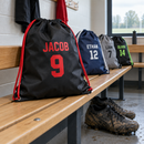 Personalised football boot bag with name and number on a changing room bench