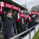 Supporters holding up red and white satin scarves printed with their team name
