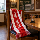 Custom satin football scarf with team name draped over a chair beside a trophy