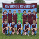 Grassroots team photo in front of a custom flag with team name on the pitch rail