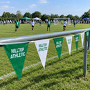 Personalised club bunting along a grassroots pitch railing on tournament day