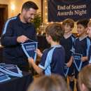 Coach handing out personalised team pennants at an end of season awards night