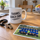 Thank you coach mug on a kitchen table beside a whistle and team photo