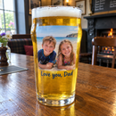 Nonic pint of lager with a colour family holiday photo print in a pub