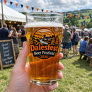 Hand holding a colour-printed beer festival pint glass outdoors