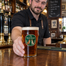 Barman serving a pint in a colour-printed pub logo glass
