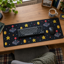 Top-down view of a pixel art desk mat with keyboard, mouse and a cup of tea