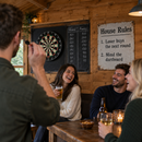 Shed bar with a dartboard and a metal house rules sign reading 'Loser buys the next round'