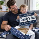 Dad unwrapping a navy last orders sign reading 'Daddy's Bar' on Father's Day