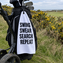 Swing Swear Search Repeat golf towel on a golf bag next to the rough