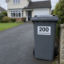 Personalised wheelie bin sticker on a grey bin at the end of a driveway