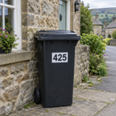 Personalised wheelie bin sticker on a black bin by a stone cottage