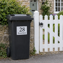 Personalised wheelie bin sticker on a black bin by a cottage gate