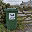 Personalised wheelie bin sticker on a green bin by a farmhouse gate