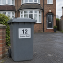 Personalised wheelie bin sticker on a grey bin outside a semi-detached house
