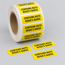 Roll of yellow allergen warning stickers printed Contains Nuts with a bakery name