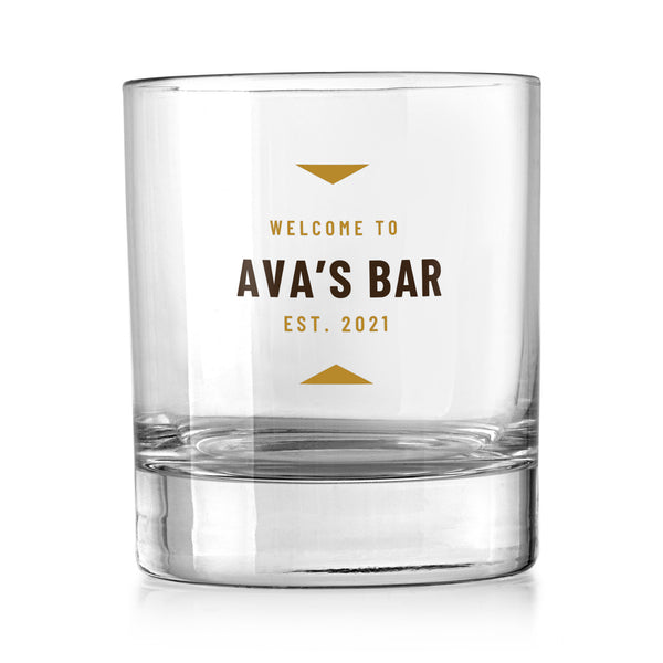 Personalised walnut and gold whisky tumbler with a walnut brown bar name and gold Welcome to and Est. lines, UV DTF printed on a clear whisky tumbler