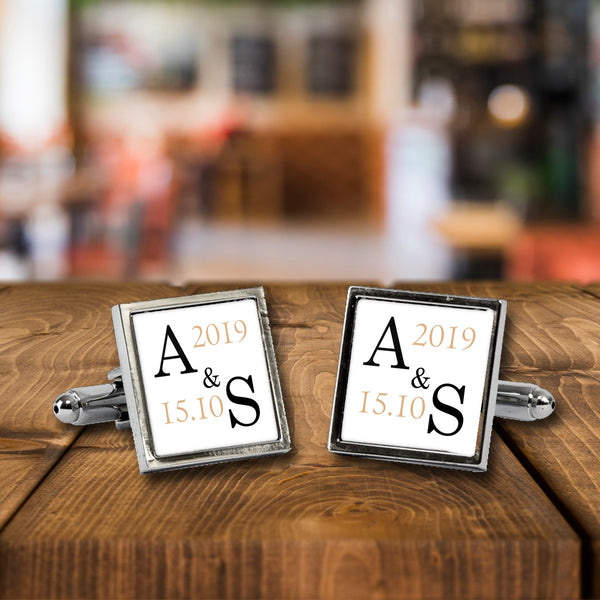 Personalised Wedding Initials Monogram cufflinks, a chrome square pair with white print on a wooden bar table